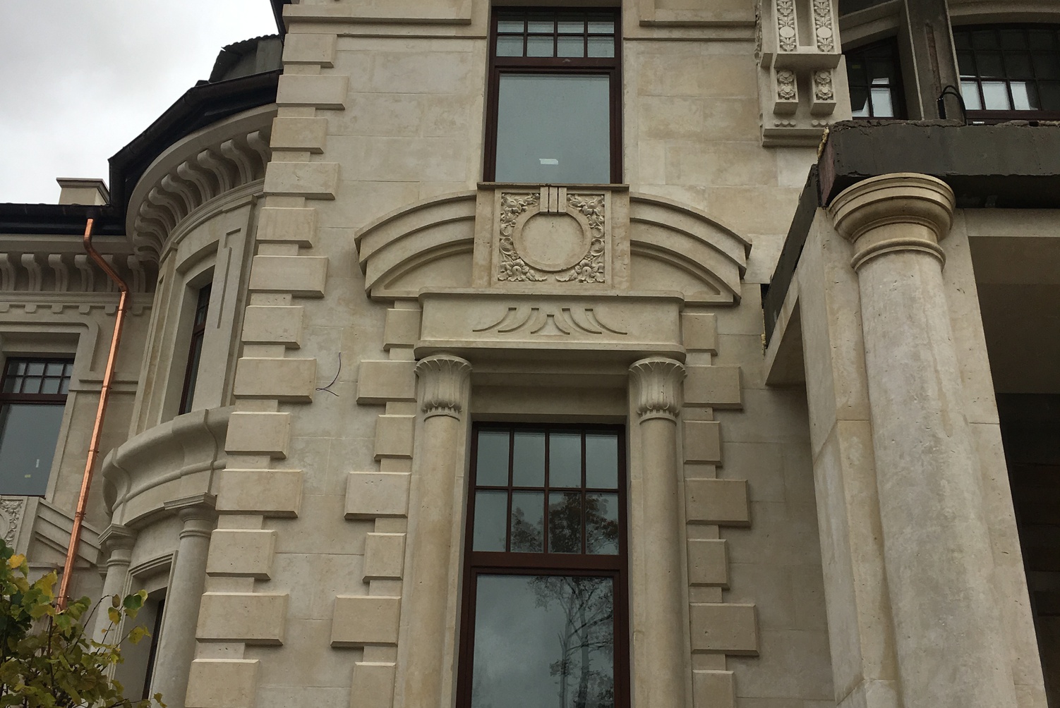 Элегантный особняк в классическом стиле с арочными проёмами, колоннами и балюстрадами. Фасад сочетает светлые тона и изысканные архитектурные детали — идеальный пример роскошного частного дома.